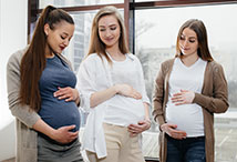 three pregnant women standing side by side